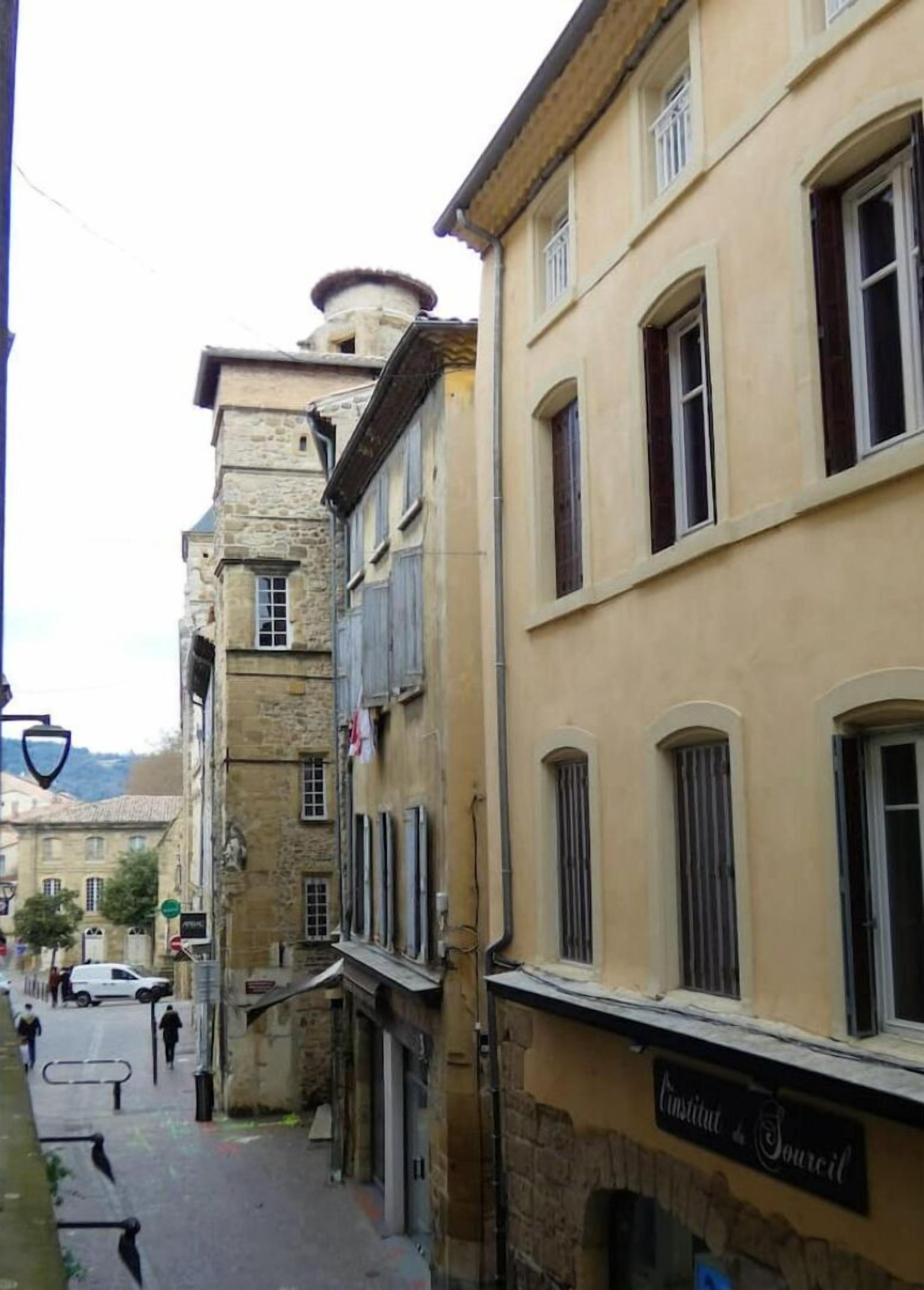 A narrow street lined with historic buildings, some with stone facades and others with plaster. A sign for 'Conseil' is visible on one building.
