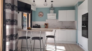A modern kitchen with white cabinets, a marble countertop, and a dining area with metal chairs. - T2 new, cap d'antibes, very comfortable, terrace, air conditioning, PK (Antibes)