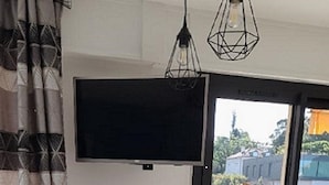A dining area with a wooden table, two black chairs, a TV mounted on the wall, and a view of the outside balcony. - T2 new, cap d'antibes, very comfortable, terrace, air conditioning, PK (Antibes)