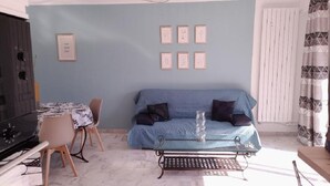 A living room with a blue sofa, a coffee table, a dining table with chairs, and framed artwork on the wall. - T2 new, cap d'antibes, very comfortable, terrace, air conditioning, PK (Antibes)