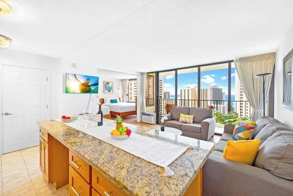 A modern apartment with a kitchen island, a living area with a sofa and a dining table, and a large window with a city view.