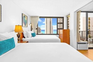 Habitación de hotel con dos camas, una ventana con vista a la ciudad, un aparador de madera y un balcón.