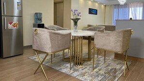 A modern dining area with a marble table, gold-legged chairs, and a water dispenser.