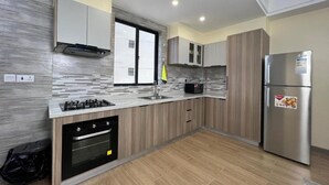 A modern kitchen with a built-in oven, a stainless steel refrigerator, and a window above the sink.