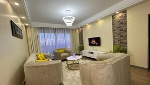 A modern living room with two sofas, a coffee table, a TV, and a stone accent wall.