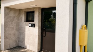 A modern building entrance with a door, a small window, and a control panel.