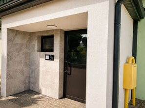 A modern building entrance with a door, a small window, and a control panel.