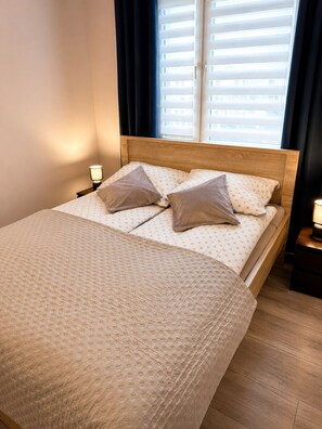 A neatly made bed with a patterned bedspread, two pillows, and a wooden headboard. - BAIO Apart Sapphire (Libiaz)