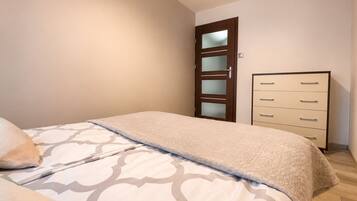 Une chambre à coucher comprenant un lit, une commode et une porte dont les panneaux sont en verre dépoli.