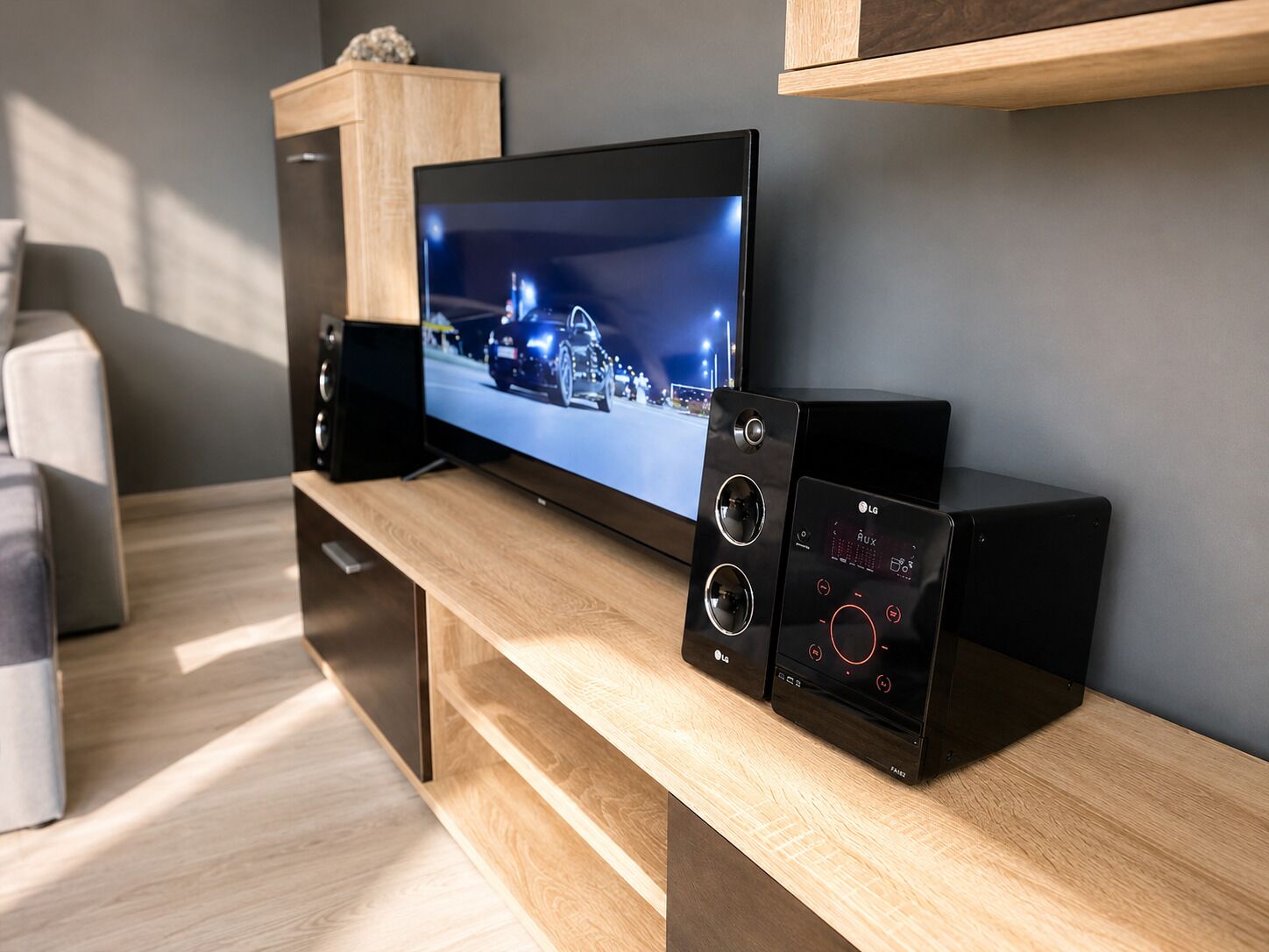 Un soggiorno moderno con una TV a schermo piatto, due diffusori neri e un mobile porta TV in legno.