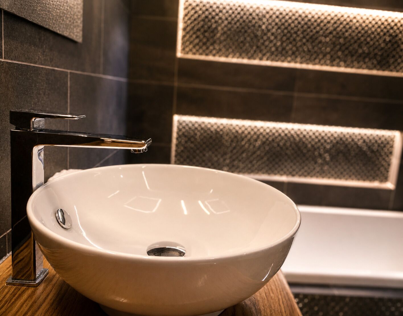 Un bagno con un lavandino bianco, un rubinetto cromato e una parete strutturata.
