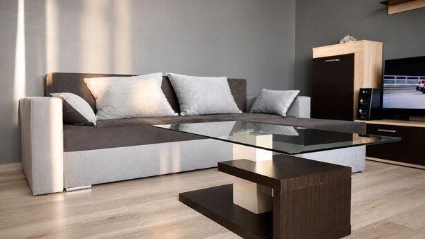 A modern living room with a sofa, a glass coffee table, and a TV.