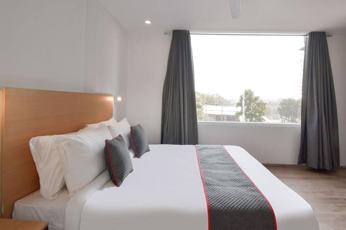 Une chambre d’hôtel avec un lit, un ventilateur de plafond et une fenêtre avec des rideaux.