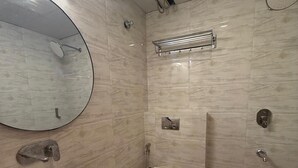 Un baño con espejo redondo, lavabo, inodoro y zona de ducha.
