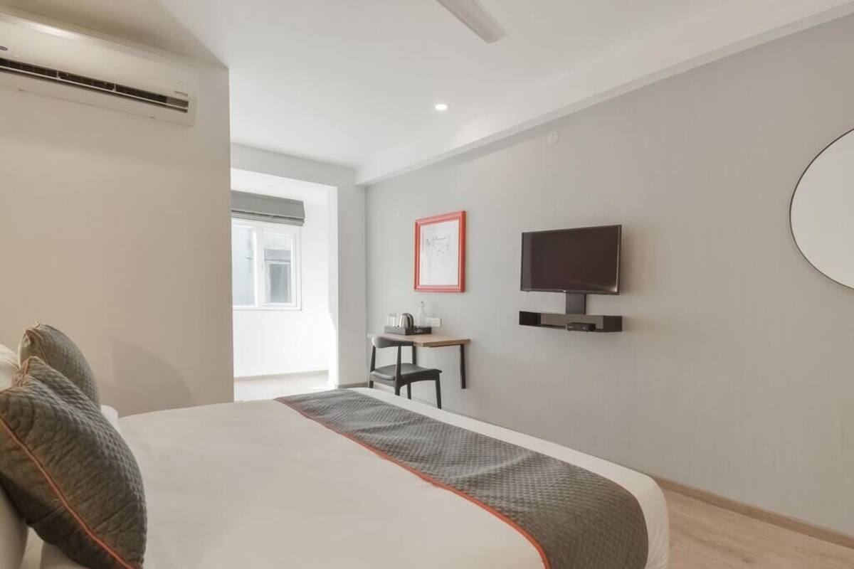 Une chambre d’hôtel moderne, dotée d’un grand lit, d’un bureau, d’une télévision et d’une fenêtre.
