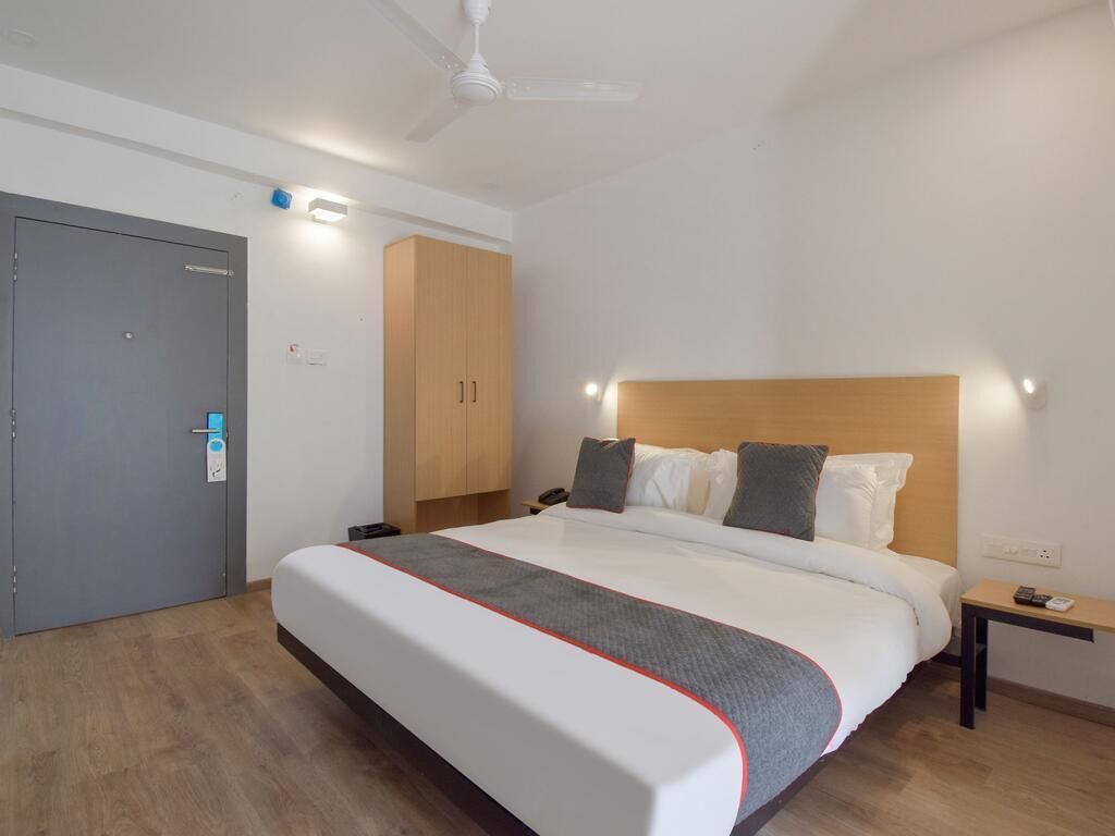 Une chambre d’hôtel comprenant un lit, une table de chevet, une commode, une armoire et une porte.