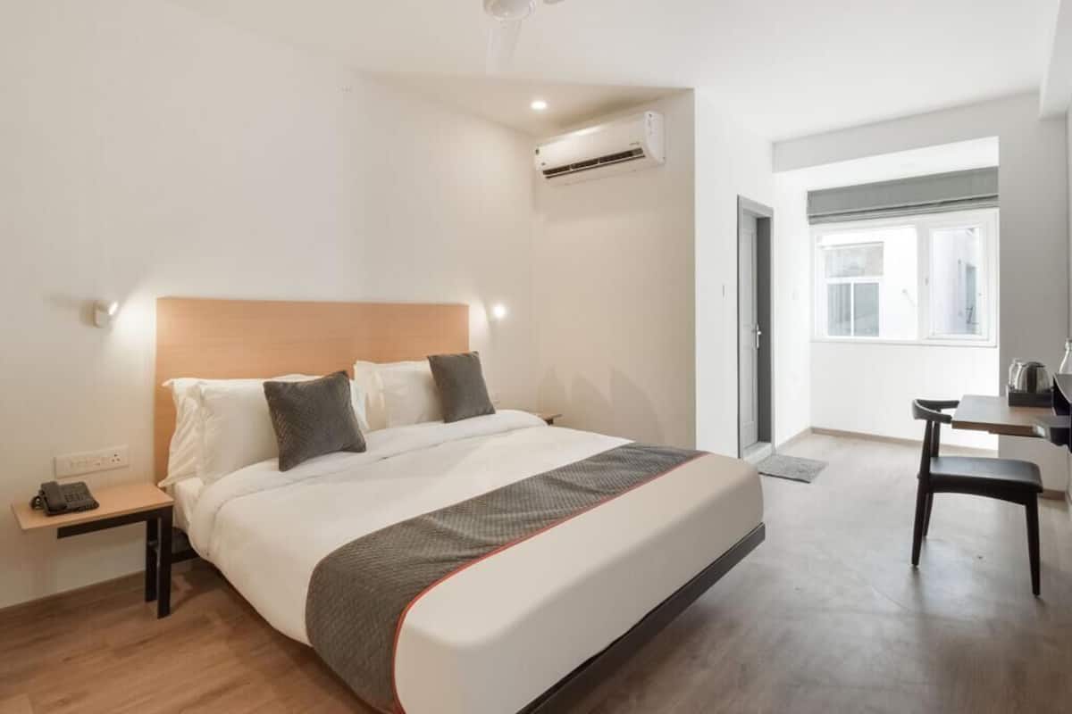 Une chambre d’hôtel équipée d’un lit, d’une table de chevet, d’une chaise et d’un ventilateur de plafond.