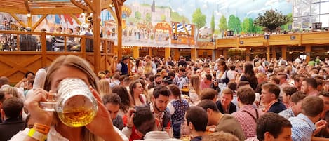 Een drukke binnenshuis gelegenheid met houten constructies en een feestelijke sfeer.