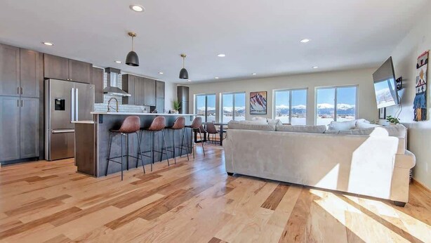 A modern kitchen with a central island, bar stools, and a large window offering a mountain view.