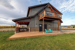 A large wooden house with a balcony and outdoor seating area.
