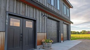 A two-story building with a garage door number 4704, a large planter with flowers, and a clear sky in the background.