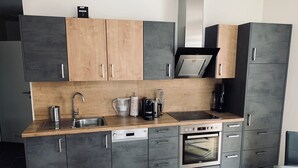 A modern kitchen with grey cabinets, a wooden countertop, a built-in oven, and a coffee machine. - Kumitzblick: A Modern, High-End Vacation Rental (Pichl-Kainisch)