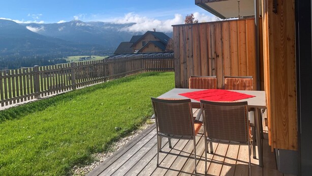 A wooden deck with a table and chairs, overlooking a mountainous landscape. - Kumitzblick: A Modern, High-End Vacation Rental (Pichl-Kainisch)