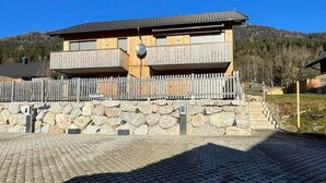 A wooden building with a balcony, a stone wall, and a sign that reads 'Kappes 10'. - Kumitzblick: A Modern, High-End Vacation Rental (Pichl-Kainisch)