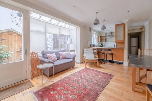 A spacious living area with a sofa, a dining table, and a kitchen in the background.