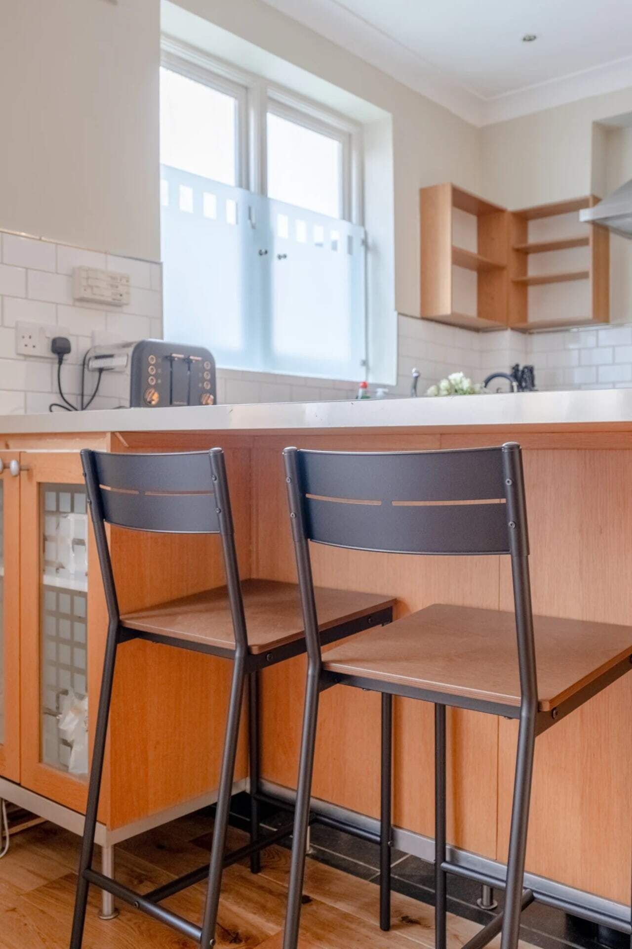 Una cocina con dos taburetes de bar, una ventana y una encimera.