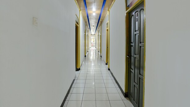 A long, narrow hallway with white tiled floors and yellow-painted walls. - Hotel O Penginapan Aina Syariah (Lebaho Ulaq)