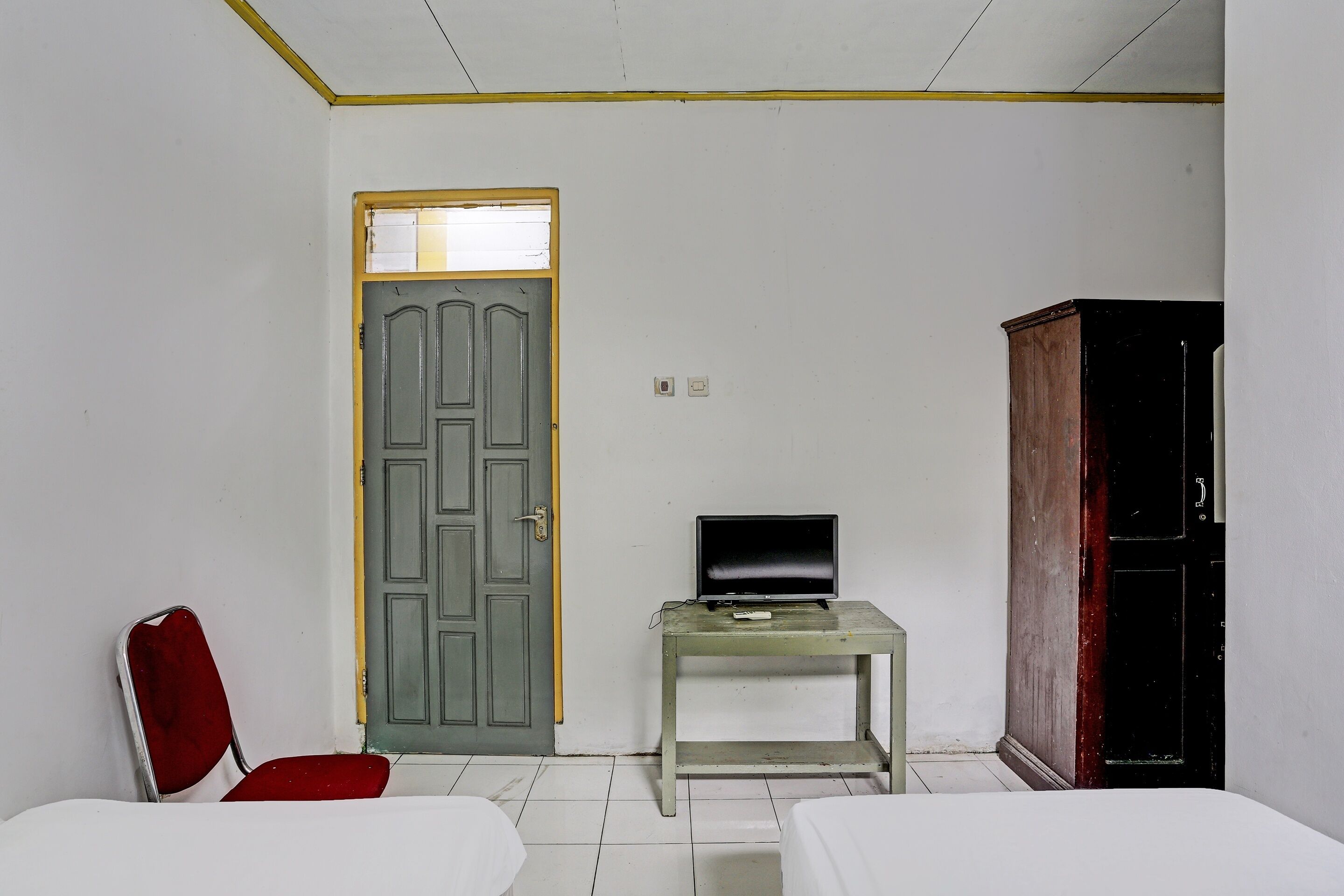 Una habitación con una cama, una silla, un escritorio con televisor y un armario.