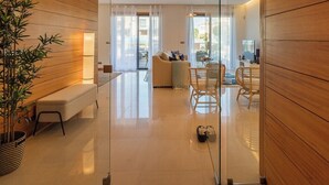 A modern living room with a sofa, chairs, a dining table, and a large window. - Vale Lobo Golf & Beach with Private Pool II (Almancil - VALE DO LOBO)