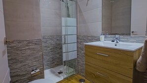 Une salle de bain moderne avec une douche à parois de verre, un meuble-lavabo en bois et un grand miroir.