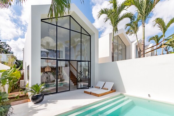 A modern house with a glass facade, a pool, and a staircase leading to the interior. - Villa Tala (Canggu)