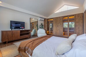 A modern bedroom with a large bed, a television, a wooden wardrobe, and a skylight. - Villa Tala (Canggu)