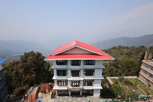 A multi-story building with a red roof and a sign that reads "Bishnu Sakyar."