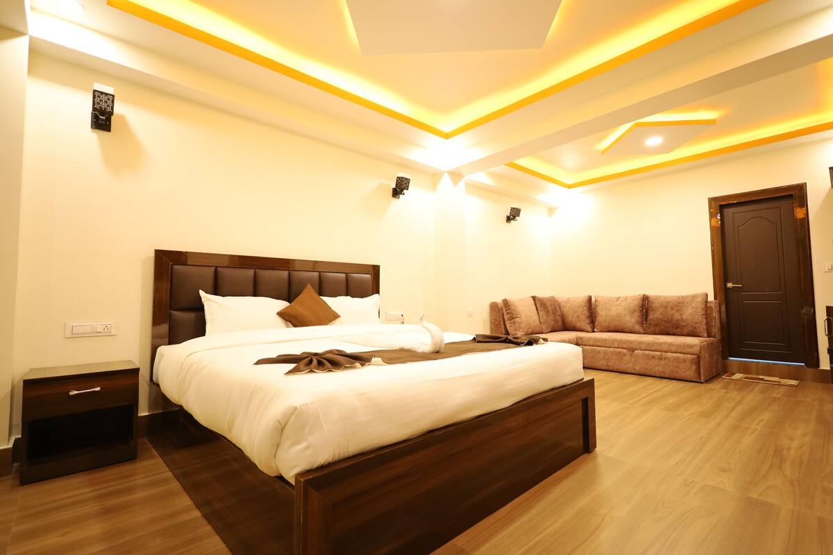 A modern bedroom with a large bed, a wooden headboard, and a brown sofa.