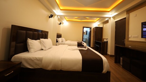 A hotel room with a large bed, a TV, and a desk. - Sikkim Sarovar (Namchi)