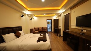 A hotel room with a large bed, a sofa, a TV, and a desk. - Sikkim Sarovar (Namchi)