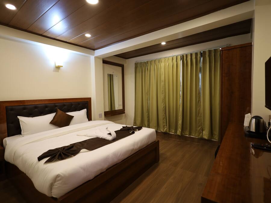 Una habitación de hotel con una cama grande, cabecera de madera y un escritorio de madera con hervidor.