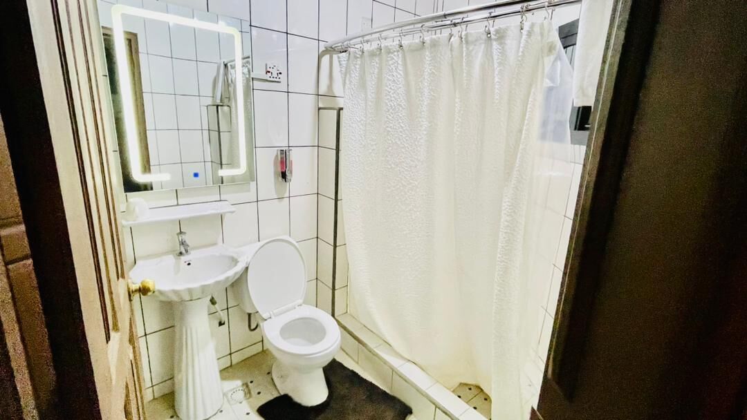 A small bathroom with a white sink, toilet, and shower curtain.