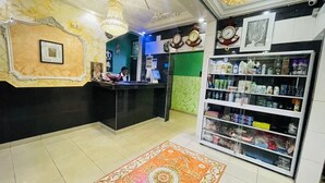 A reception area with a counter, a chandelier, a clock, and a shelf with various products. - MARVEL HOTEL BUEA (Buea)