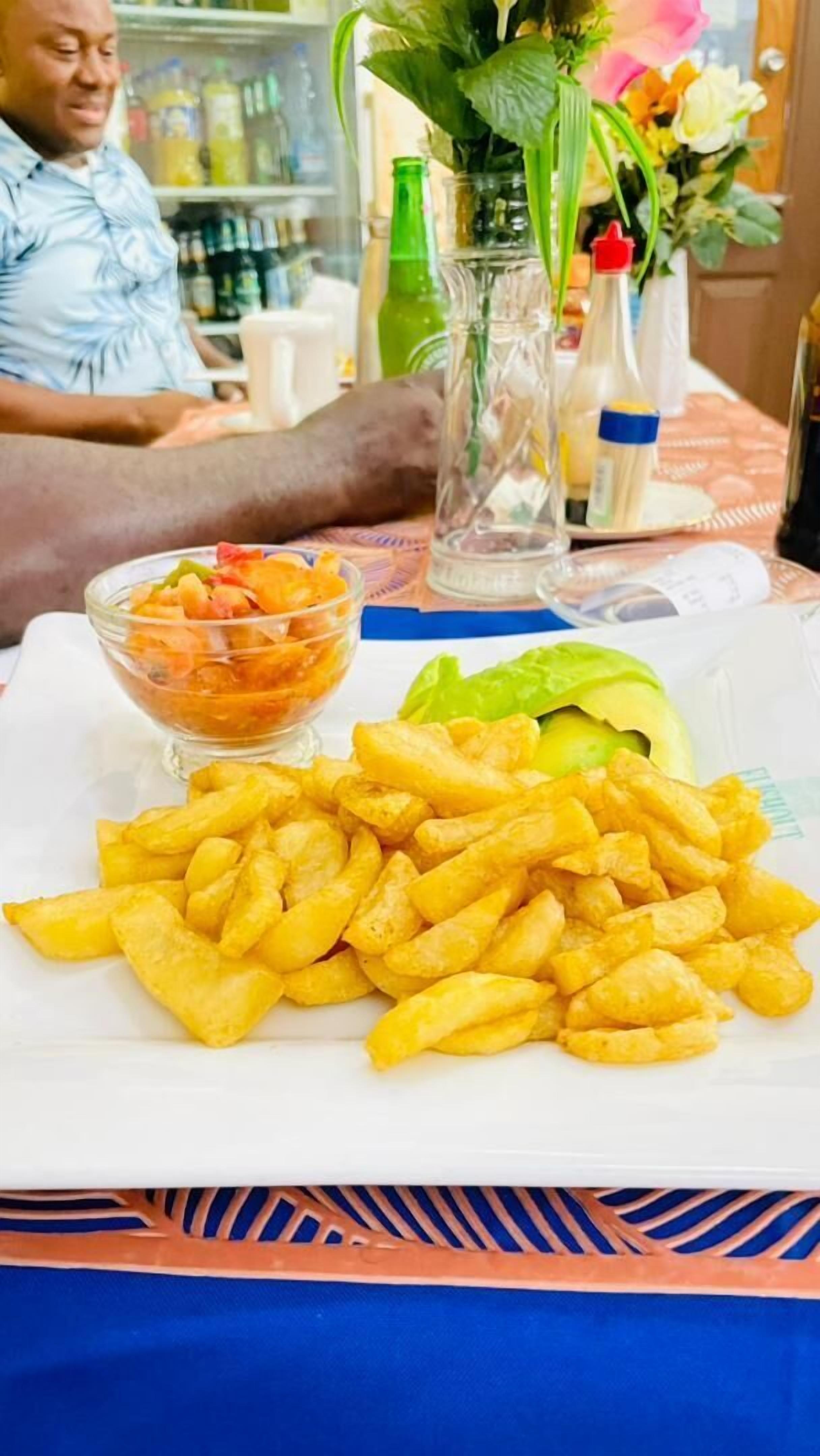 A plate with French fries, a slice of avocado, and a bowl of salad.