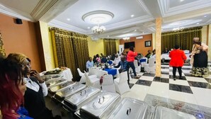 A banquet hall with round tables, white chairs, and a checkered floor. - MARVEL HOTEL BUEA (Buea)