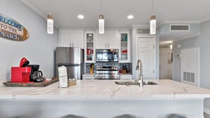 A modern kitchen with white cabinets, stainless steel appliances, and a marble countertop. - Monthly Discount! Ocean View Heated Pool Hot tub! (Galveston)