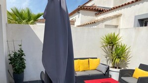 A patio with outdoor furniture, a covered area, and potted plants.