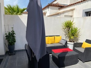 A patio with outdoor furniture, a covered area, and potted plants.