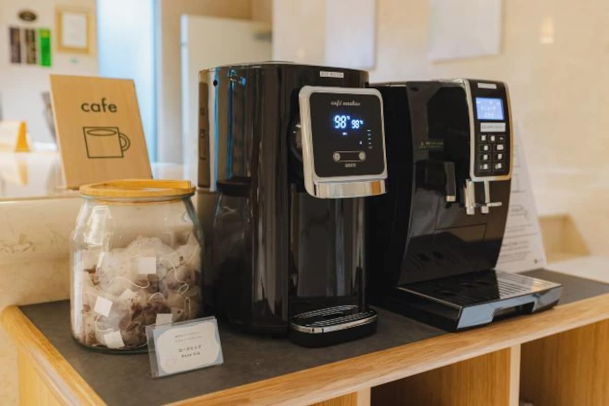 Una cafetera con pantalla digital, un tarro de granos de café y un letrero que dice 'café' sobre una barra.