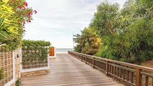 A wooden boardwalk leading to a beach, flanked by greenery and a fence. - Vale Lobo  Golf & Beach with Private Pool I (Vale do Lobo)